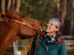 Fuchsfarbener Wallach mit Trense gibt Stephanie Richter ein Küsschen, fotografiert von LiraAmarokPictures