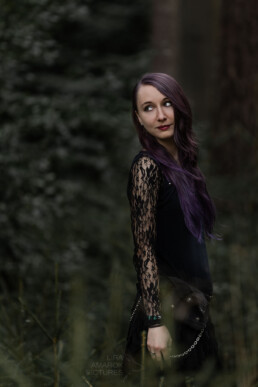 Portrait einer Frau mit lila Haaren im Wald, die zur Seite blickt, fotografiert von LiraAmarokPictures