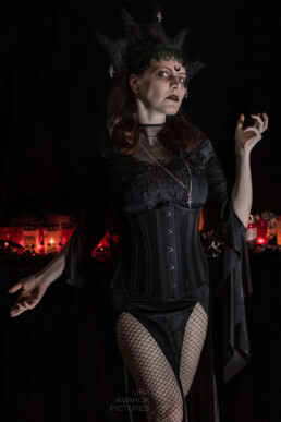 Portrait von Ines Fischer in Gothickleidung vor schwarzem Hintergrund mit Kerzen, fotografiert von LiraAmarokPictures