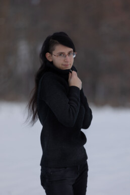 Lira in schwarzem Pullover vor Schneelandschaft stehend