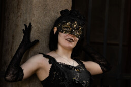 Frau mit schwarzen Handschuhen und venezianischer Maske blickt nach oben