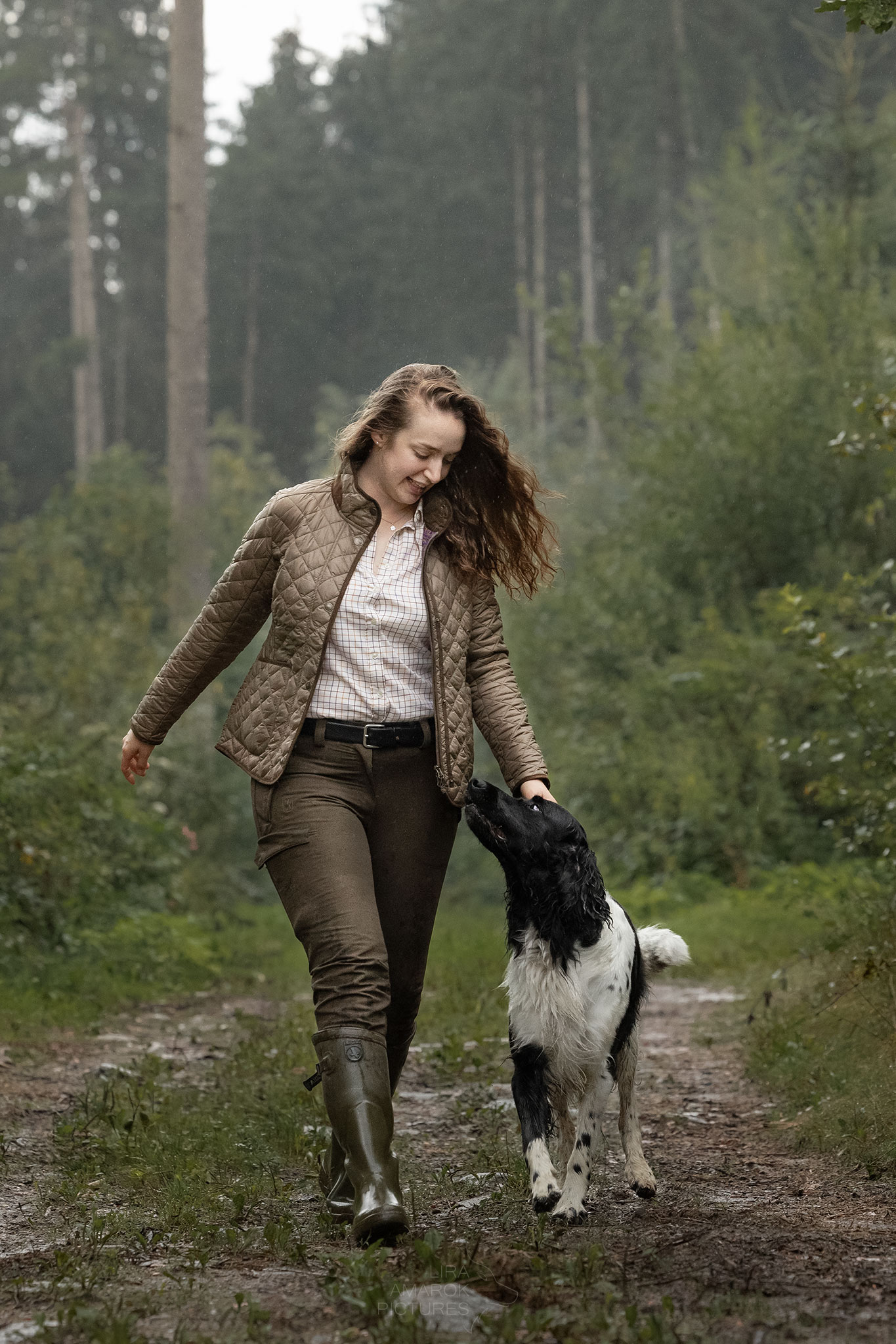 Hundeführerin und ihr Jagdhund gehen gemeinsam bei Fuß durch den Wald