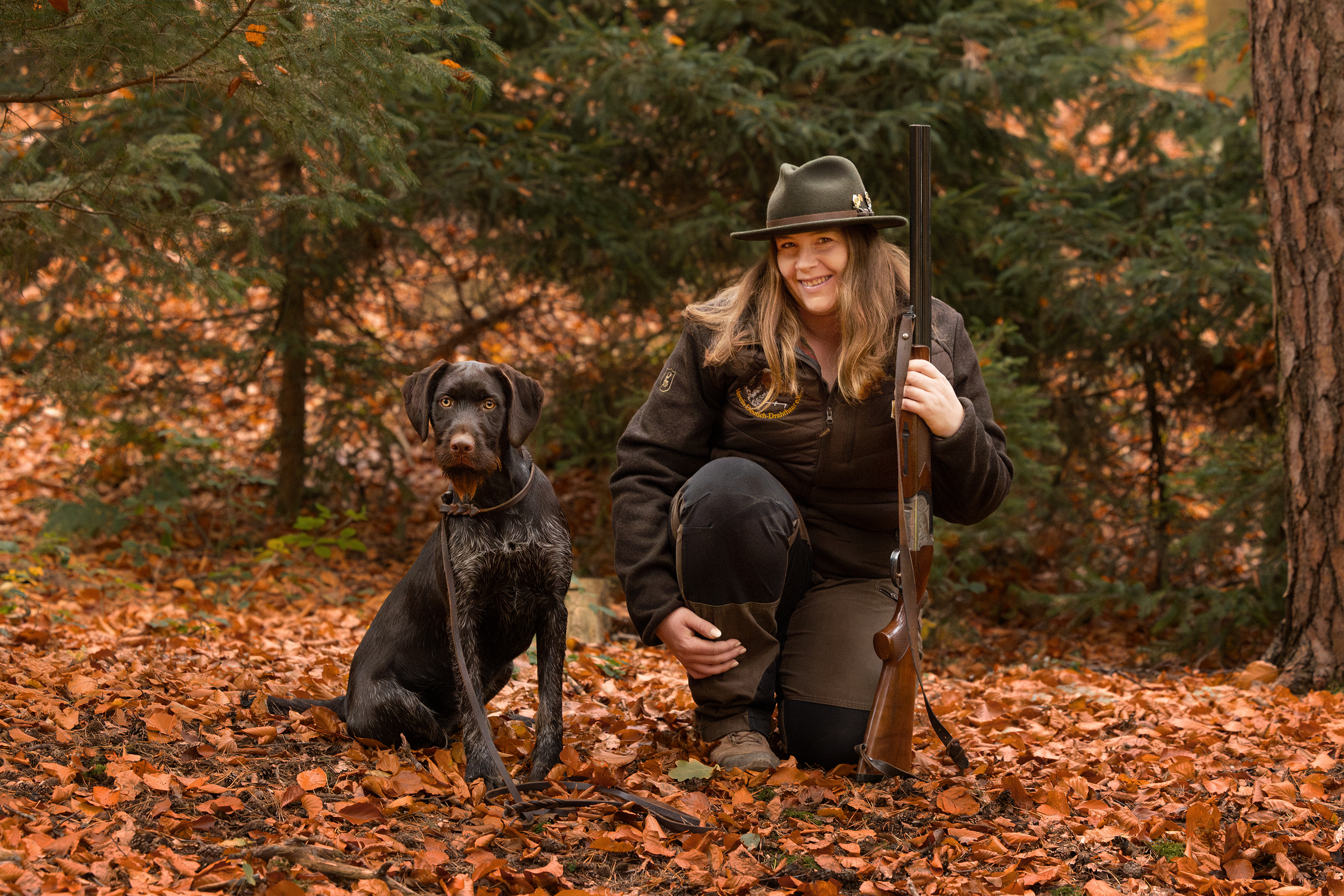 Eine Jägerin mit Flinte und ihrem Deutsch Drahthaar an ihrer Seite