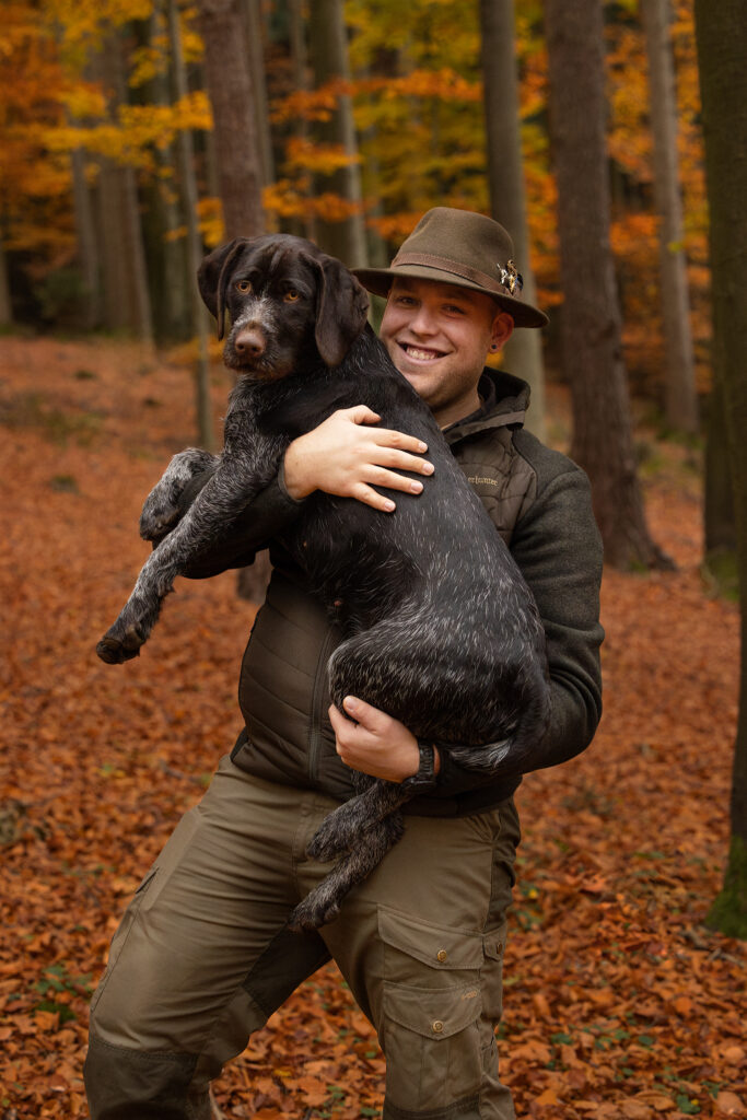 Ein Jäger mit seinem Deutsch Drahthaar auf dem Arm