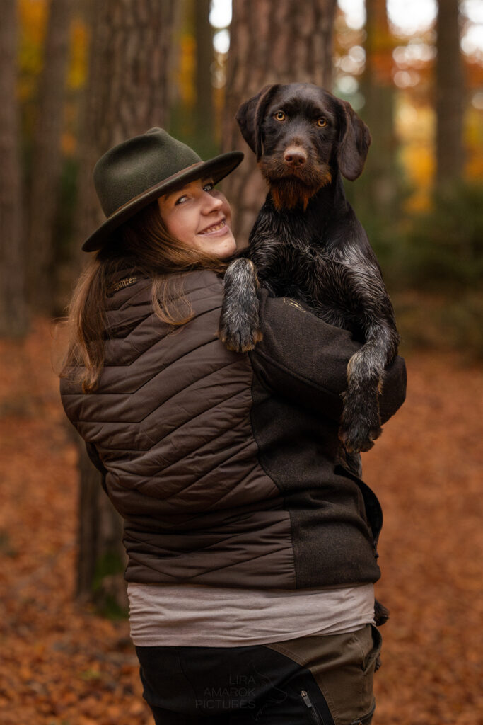 Jägerin hat ihren Jagdhund auf dem Arm