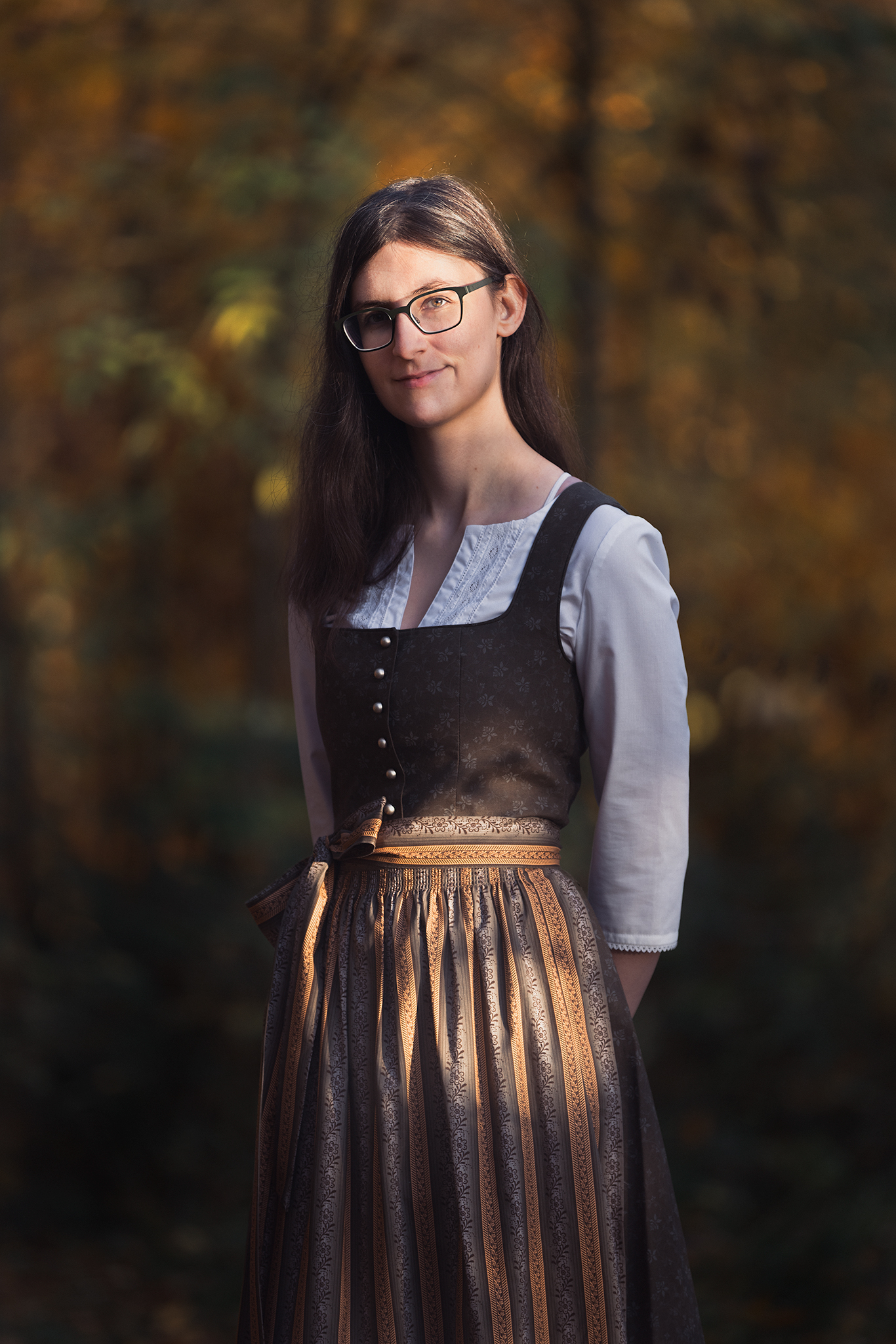 Eine braunhaarige Frau in einem grünen Dirndl mit einer orangenen Schürze