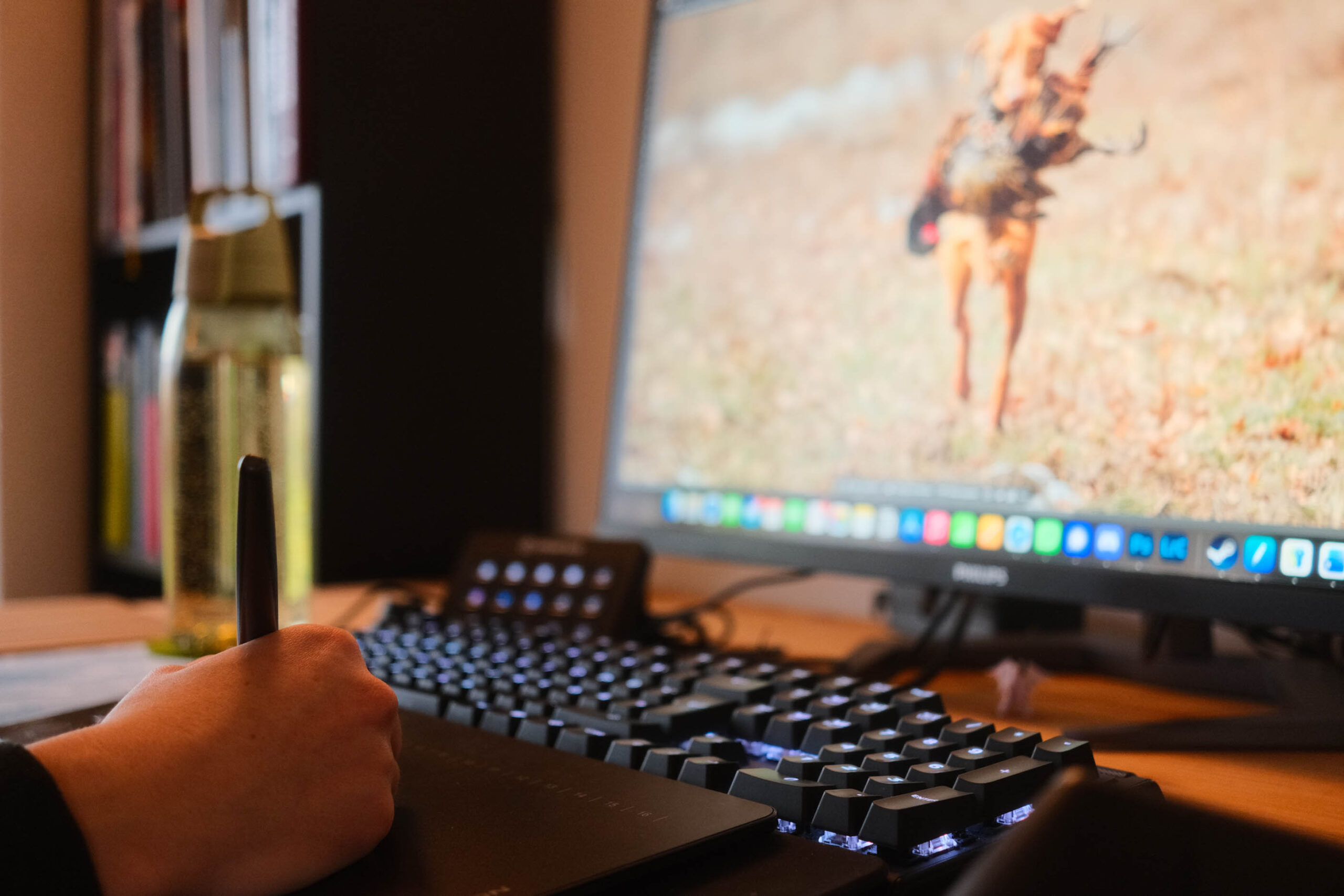 Eine Hand auf einem Grafiktablet an einem Bild bearbeitend am Schreibtisch